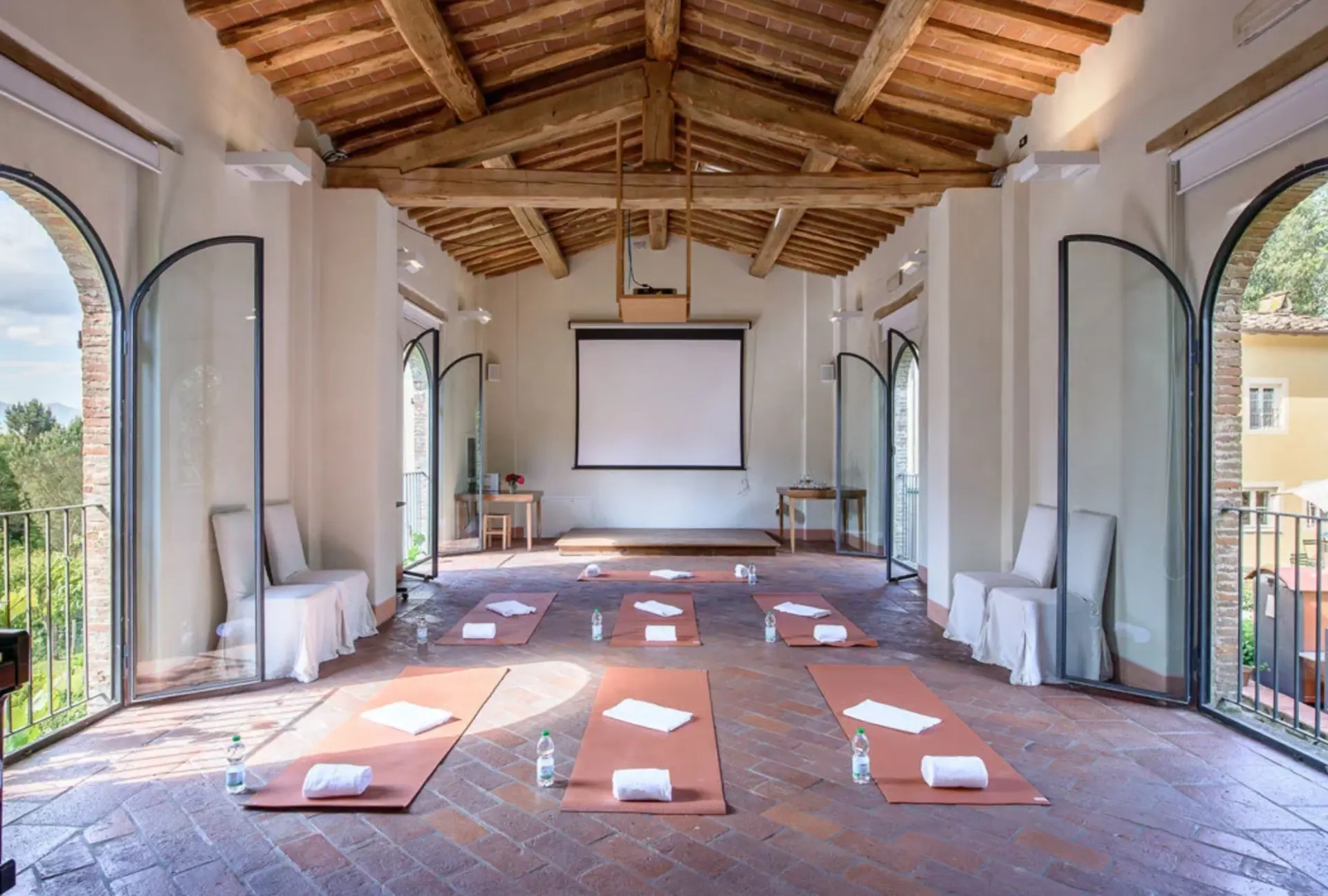 Sala del retreat ENERJè con travi in legno e tappetini Pilates disposti sul pavimento in cotto